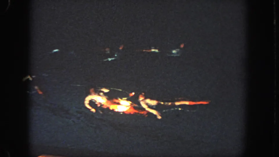 Swimmers gather into a compact formation in the dark pool during the 1951 Atlanta home-movie sequence.
