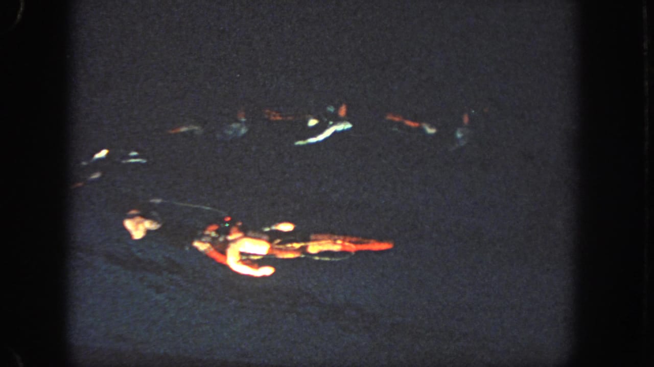 1951 Atlanta footage shows swimmers in a loose nighttime formation, partly illuminated against nearly black water.