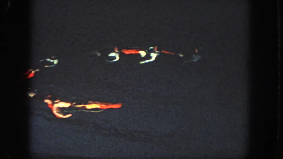 A grainy 1951 Atlanta frame shows multiple swimmers spread across a dark lake or pool during a choreographed nighttime sequence.