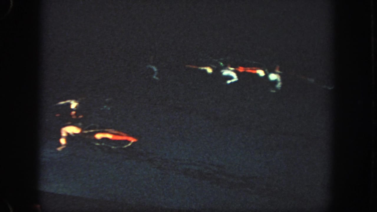 Dark 1951 Atlanta 8mm frame with soft, blurred red and white light streaks against a nearly black projected field.