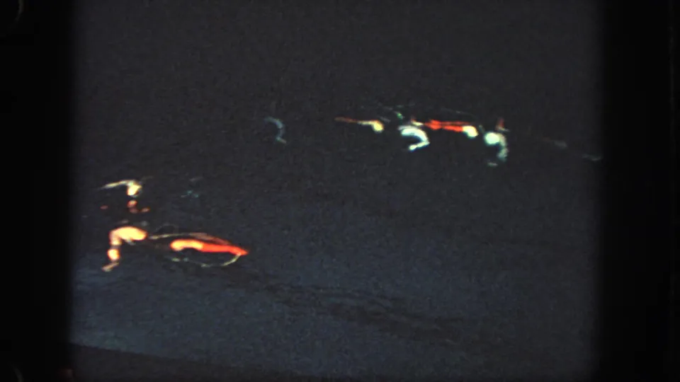 Dark 1951 Atlanta 8mm frame with soft, blurred red and white light streaks against a nearly black projected field.