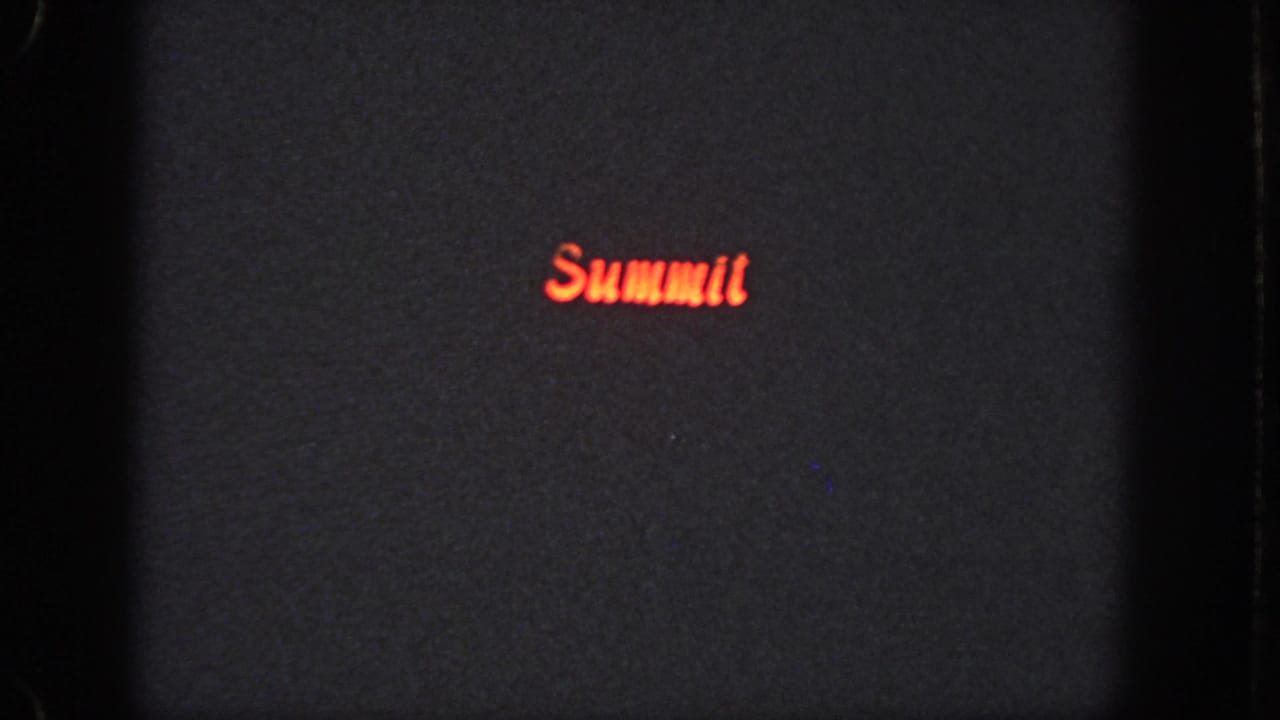 Dark 1951 Atlanta 8mm frame showing a red glowing “Summit” title or sign on a mostly black field.