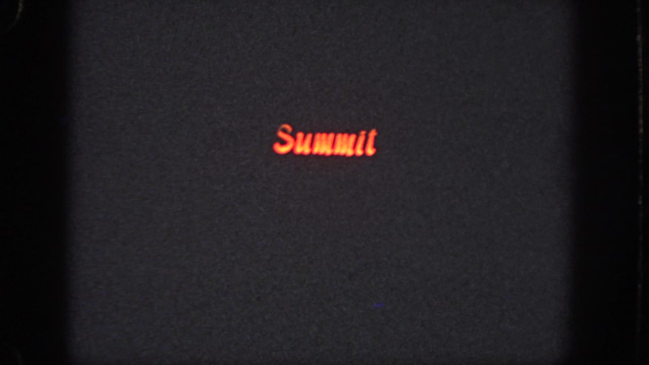 Dark grainy 8mm frame from the Atlanta reel with the red “Summit” lettering positioned low and left of center.