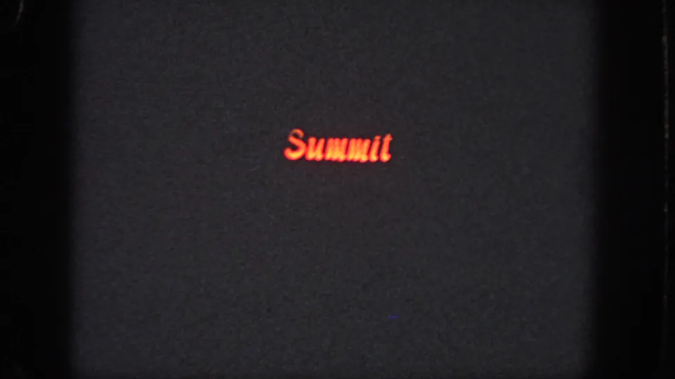 Dark grainy 8mm frame from the Atlanta reel with the red “Summit” lettering positioned low and left of center.