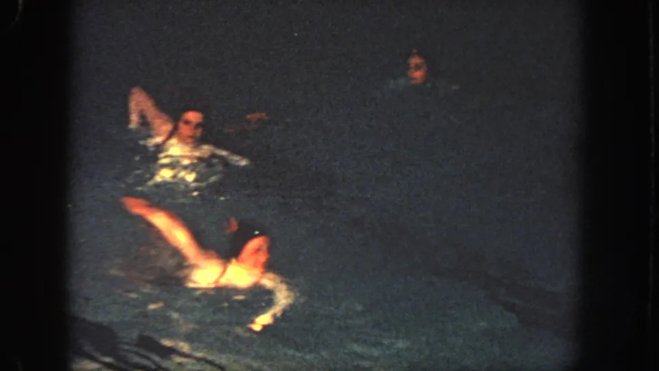 1951 Atlanta 8mm frame showing swimmers in motion at night, including a raised arm and bright reflections on the water.