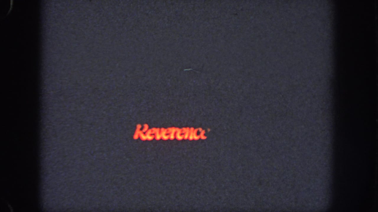 Red word Reverence on a dark film frame with gate edges and grain.