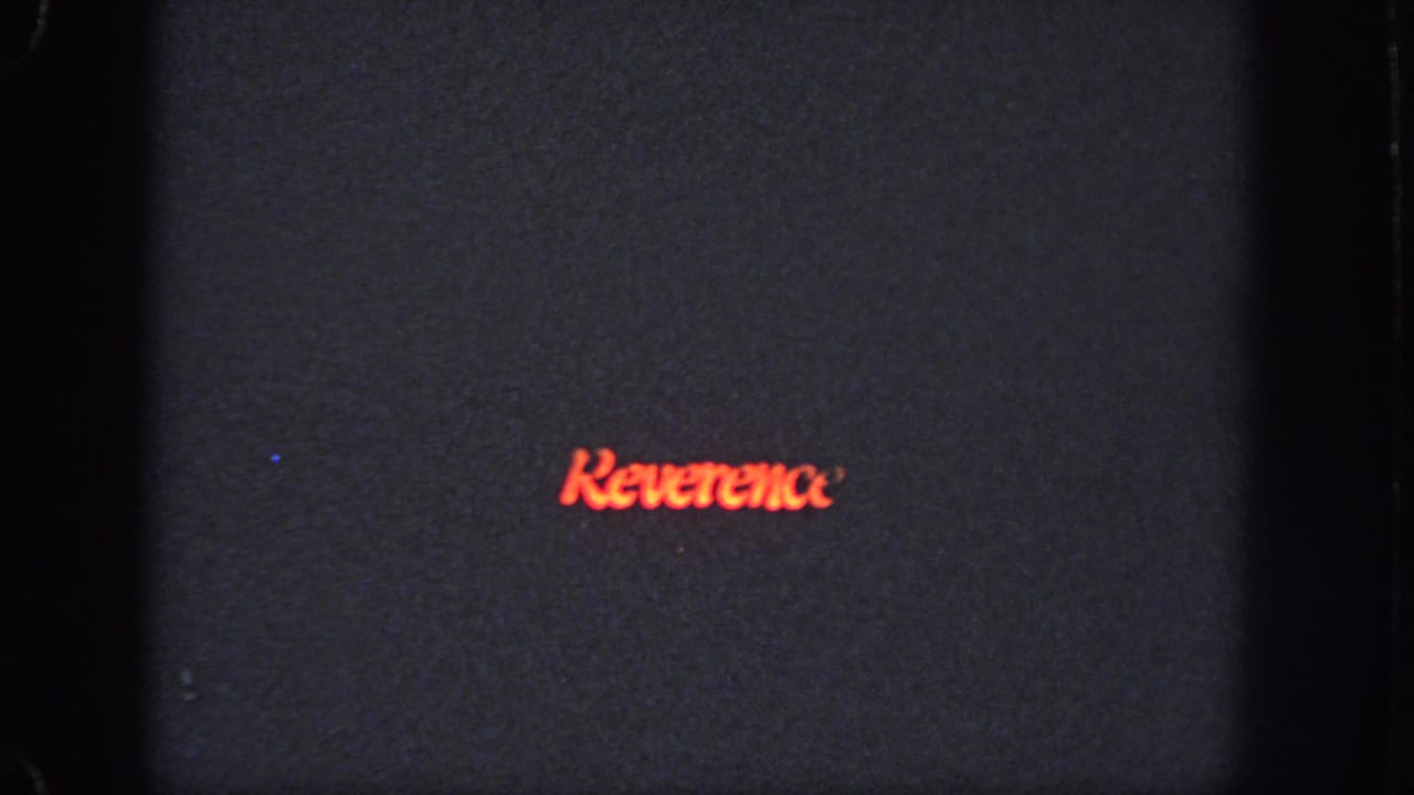 Red Reverence title remains centered on a dark, grainy frame.