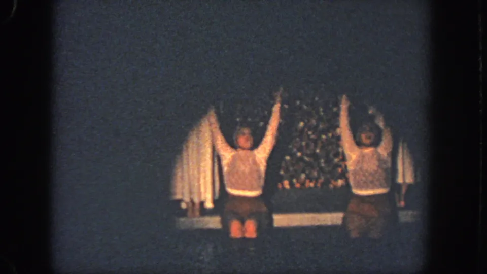 Two performers in white tops and brown shorts hold raised-arm poses on the dim 1951 Atlanta stage.