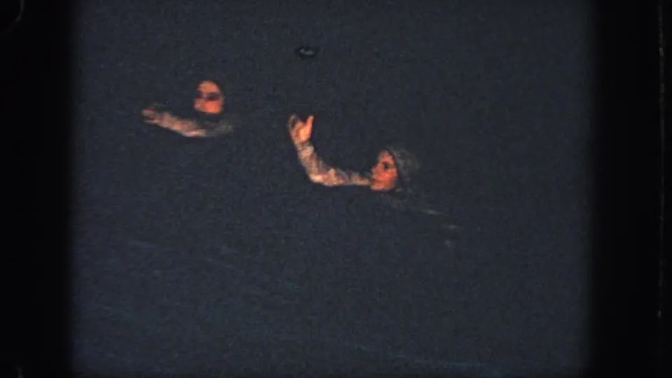 1951 Atlanta pool performance frame with two synchronized swimmers raising arms in dark water.