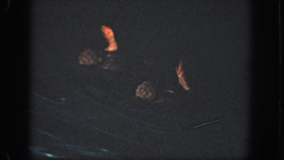 In 1951 Atlanta home-movie footage, two swimmers move through a dark pool with arms lifted in a synchronized swimming pose.