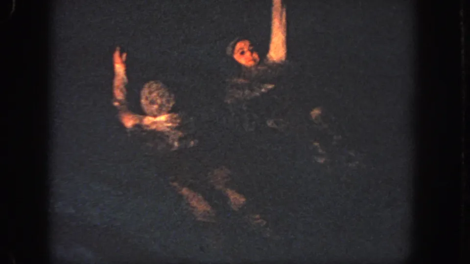 At the end of the 1951 Atlanta clip, two swimmers continue the routine in dark water, one with an arm raised high above the pool.