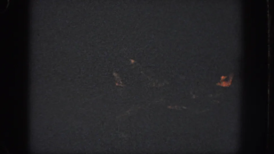 1951 Atlanta 8mm frame with swimmers mostly obscured by darkness, one face appearing near the right edge of the pool scene.