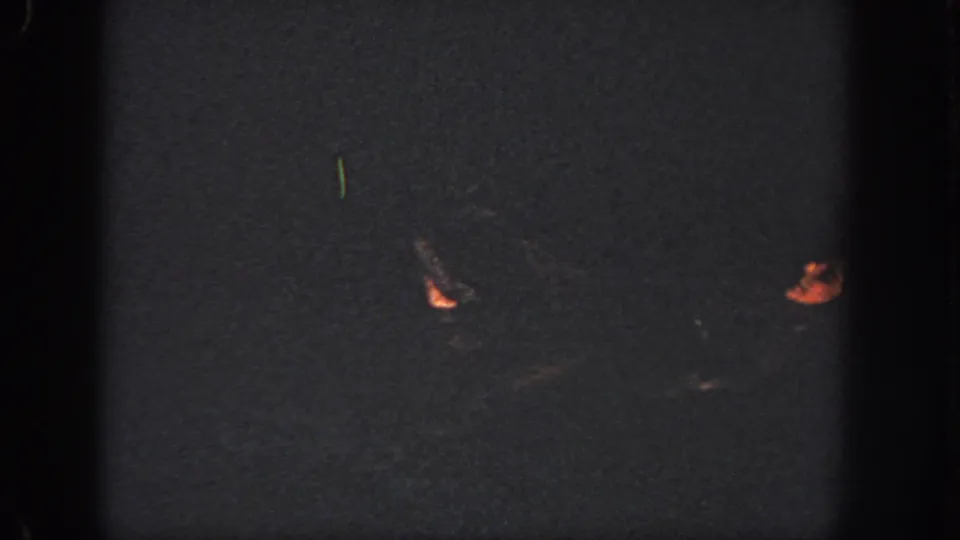 In this 1951 Atlanta home-movie frame, two swimmers' lower legs and feet appear dimly against dark pool water.