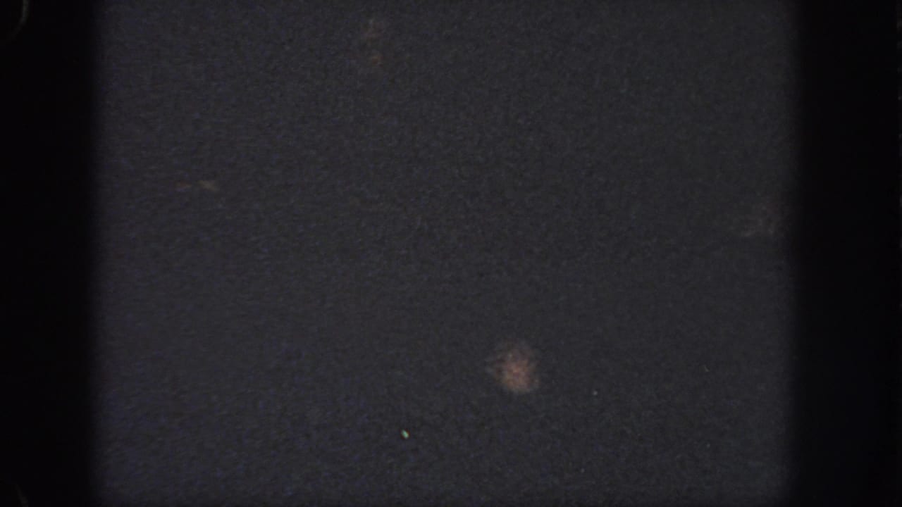 Grainy nighttime pool frame from the 1951 Atlanta home movie, with a small blurred figure or highlight in the water.