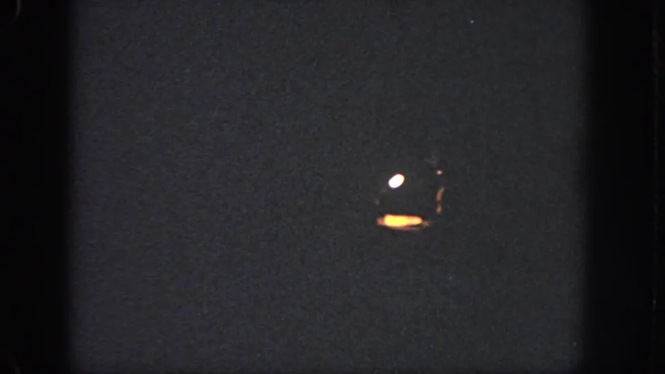 Dark pool surface with small bright reflections or flare marks in a low-exposure 1951 Atlanta 8mm frame.