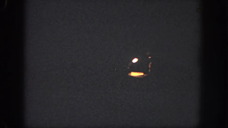1951 Atlanta 8mm frame showing a dark projected surface with a small orange glow, white reflection, grain, and soft frame edges.