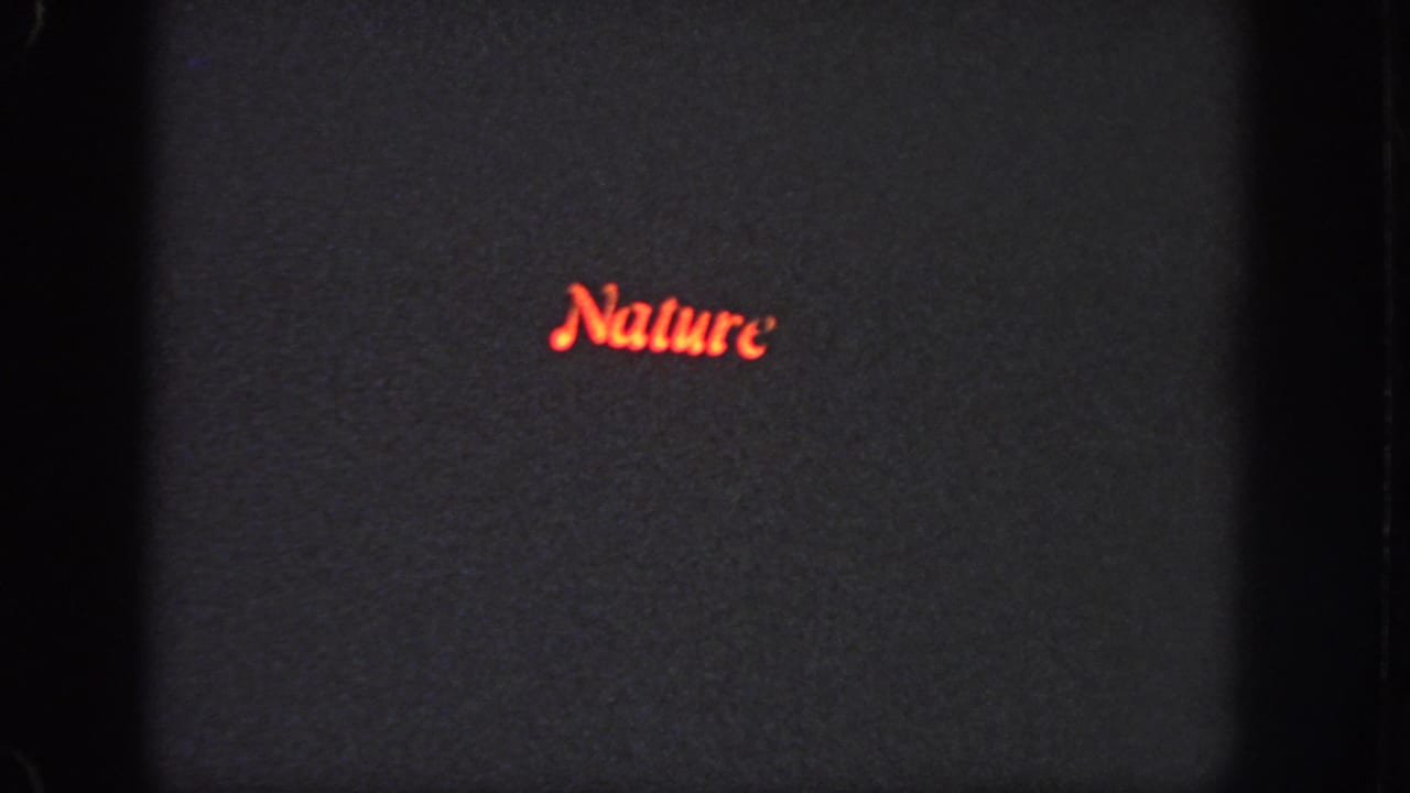 1951 Atlanta 8mm frame showing the word Nature in red cursive on a dark screen with soft focus, grain, and visible gate edge.