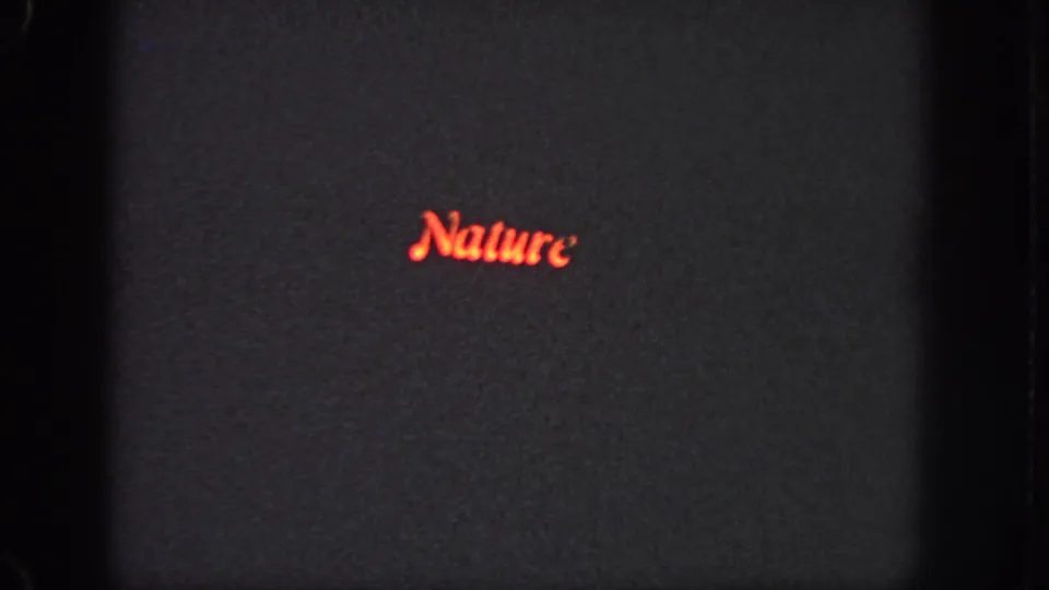 1951 Atlanta 8mm frame showing the word Nature in red cursive on a dark screen with soft focus, grain, and visible gate edge.