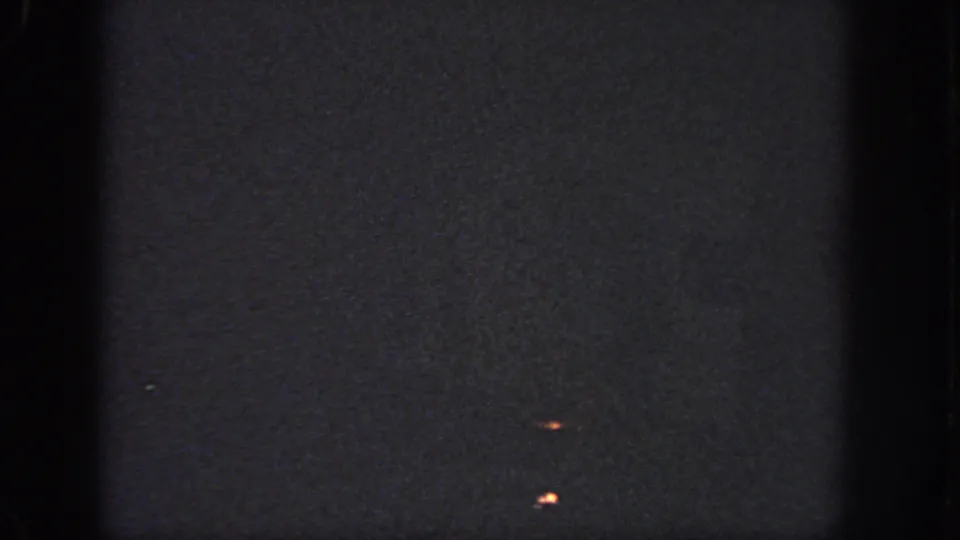 1951 Atlanta 8mm frame of a dark projected surface with small orange marks, visible grain, soft exposure, and film edge shadows.