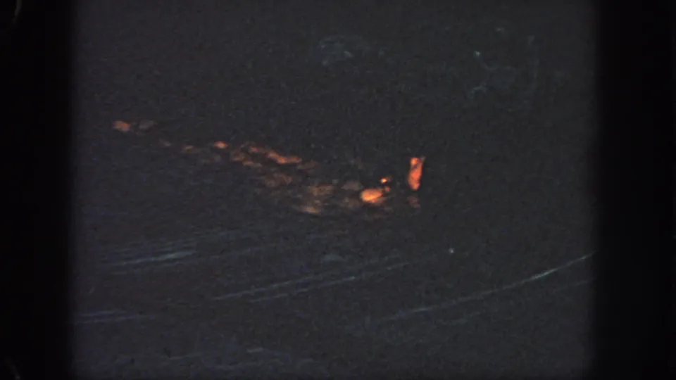 Atlanta 1951 8mm frame showing an indistinct orange-lit object or reflection on dark water at night.