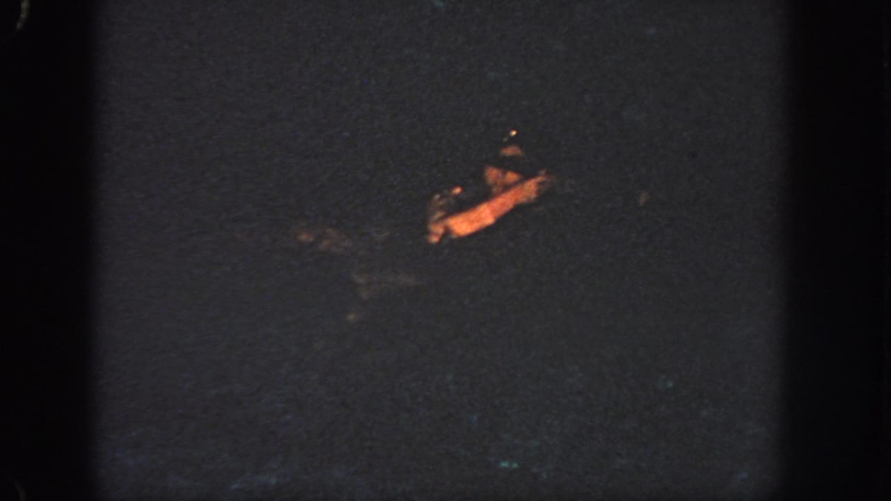 1951 Atlanta 8mm frame showing a distant person swimming through dark water, with only the face and arm catching warm light.