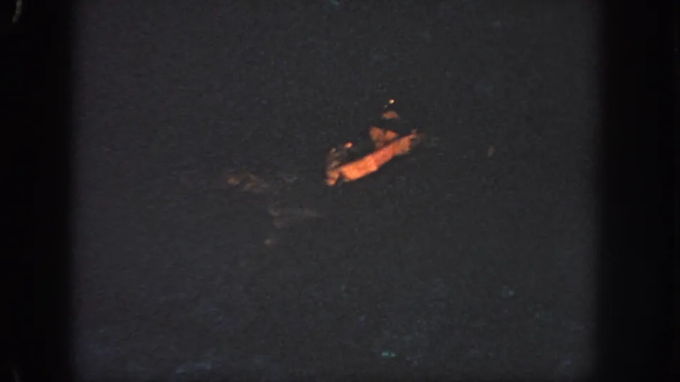 1951 Atlanta 8mm frame showing a distant person swimming through dark water, with only the face and arm catching warm light.