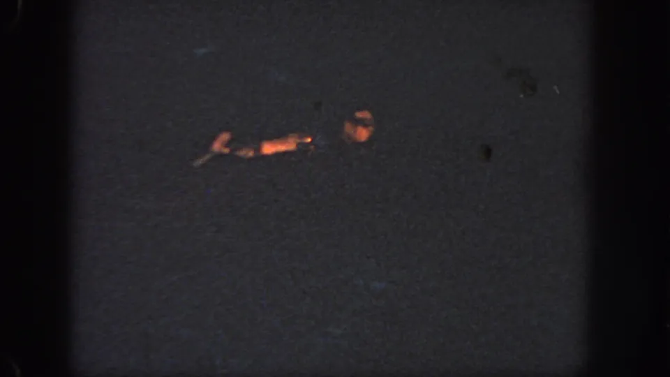 1951 Atlanta 8mm frame with a swimmer's head and extended arm briefly illuminated in a dark river at night.