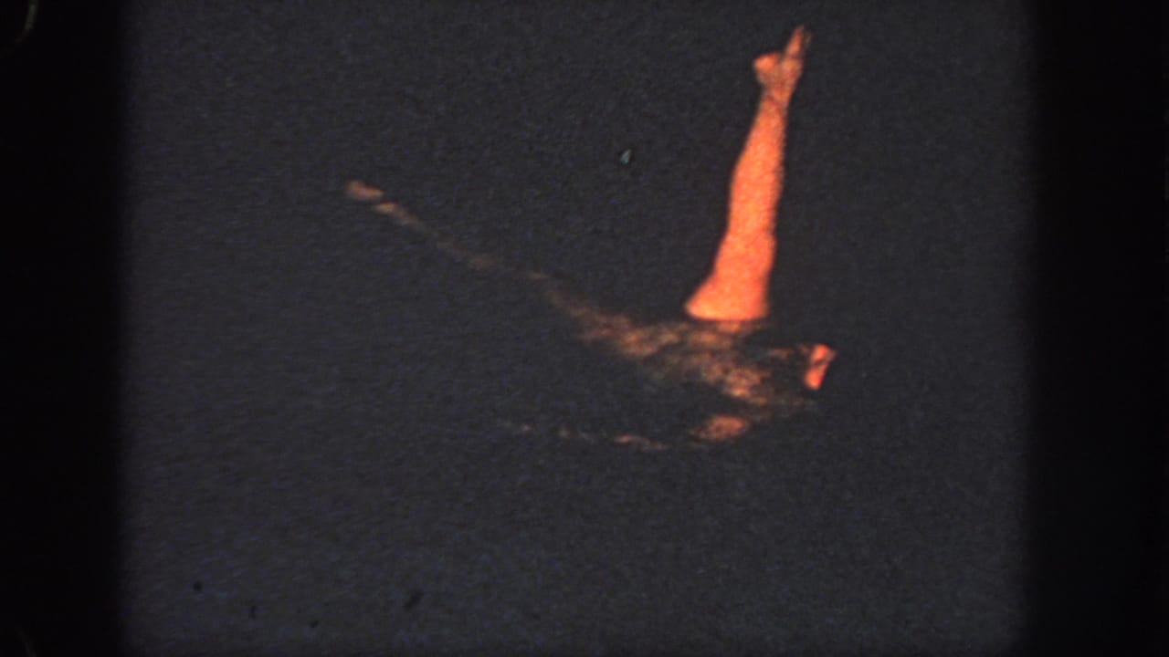 1951 Atlanta home-movie frame showing a swimmer partly lit orange against very dark water.