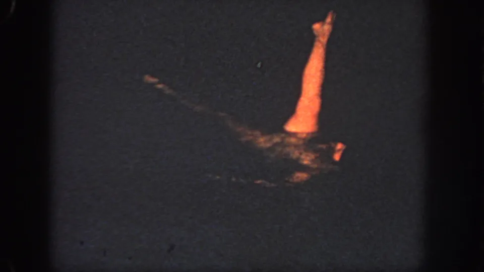 1951 Atlanta home-movie frame showing a swimmer partly lit orange against very dark water.