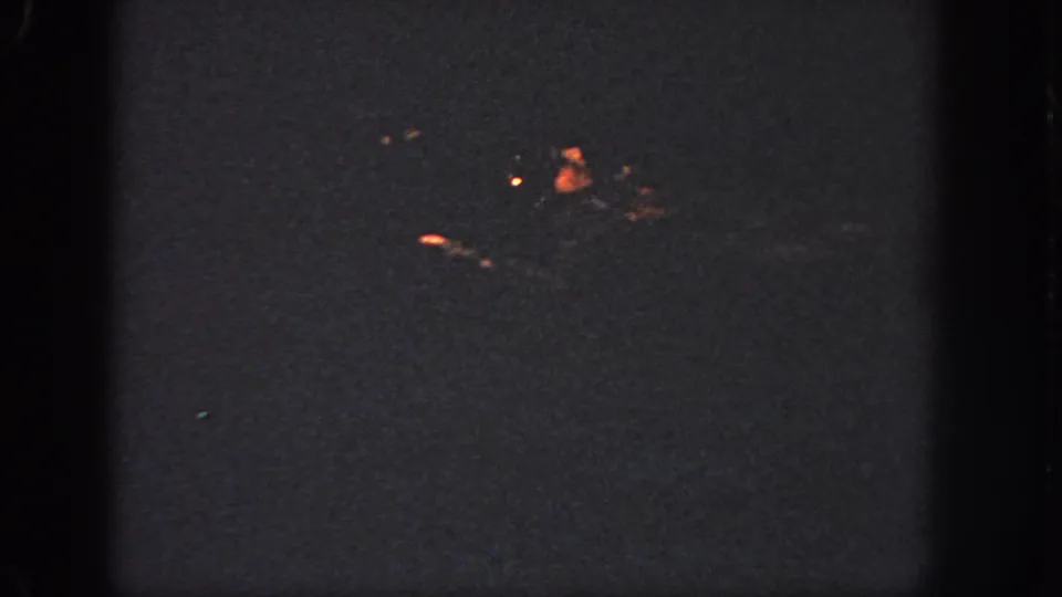 1951 Atlanta 8mm frame showing the swimmer reduced to a dim shape with small orange highlights on the water.