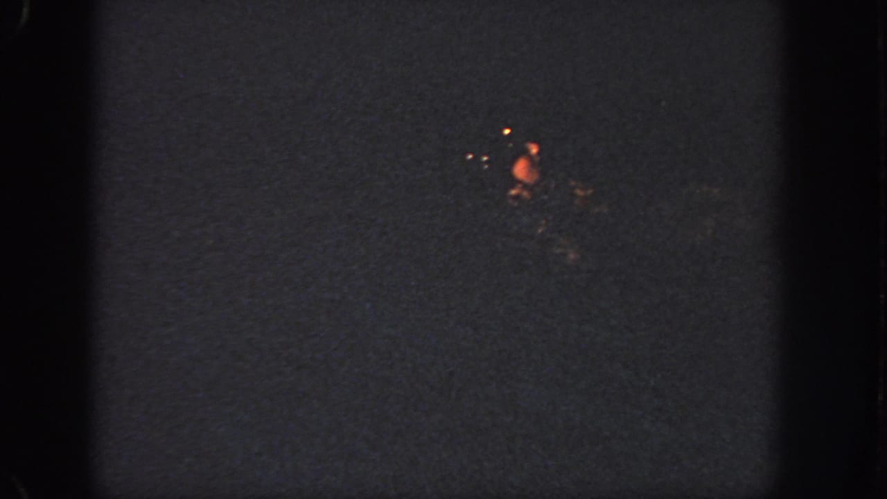 1951 Atlanta 8mm frame showing faint red-orange holiday lights against a mostly dark night background.