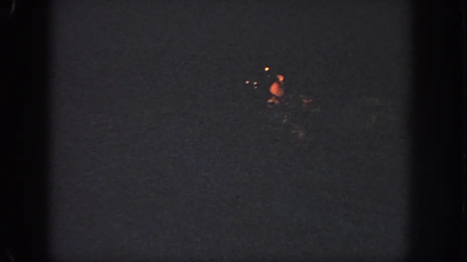 1951 Atlanta 8mm frame showing faint red-orange holiday lights against a mostly dark night background.