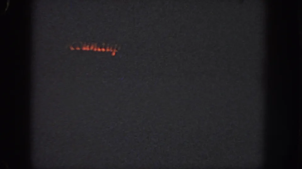 1951 Atlanta 8mm frame with a faint red-orange light streak, possibly part of a holiday display, in darkness.