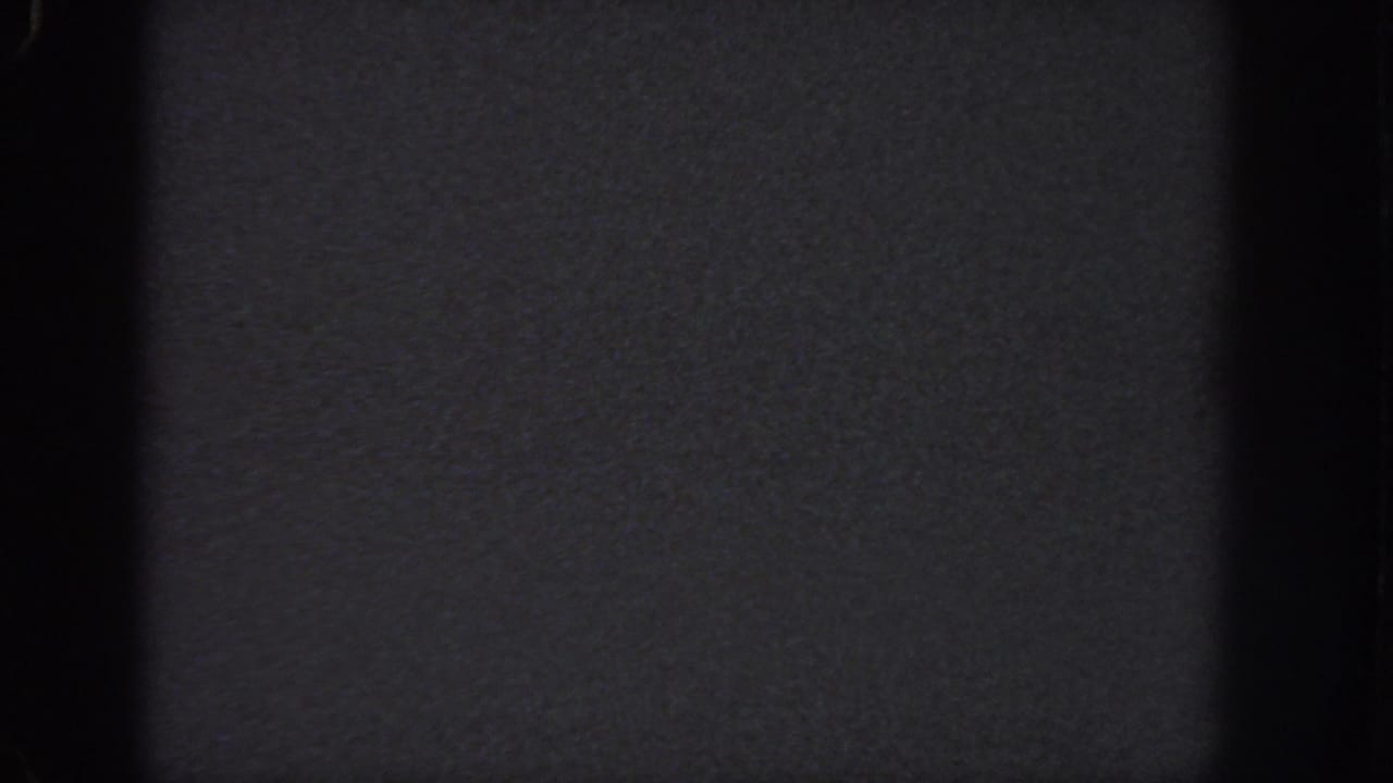 1951 Atlanta 8mm frame showing an abstract dark exposure with black vertical bands, visible grain, and no readable figures or structures.