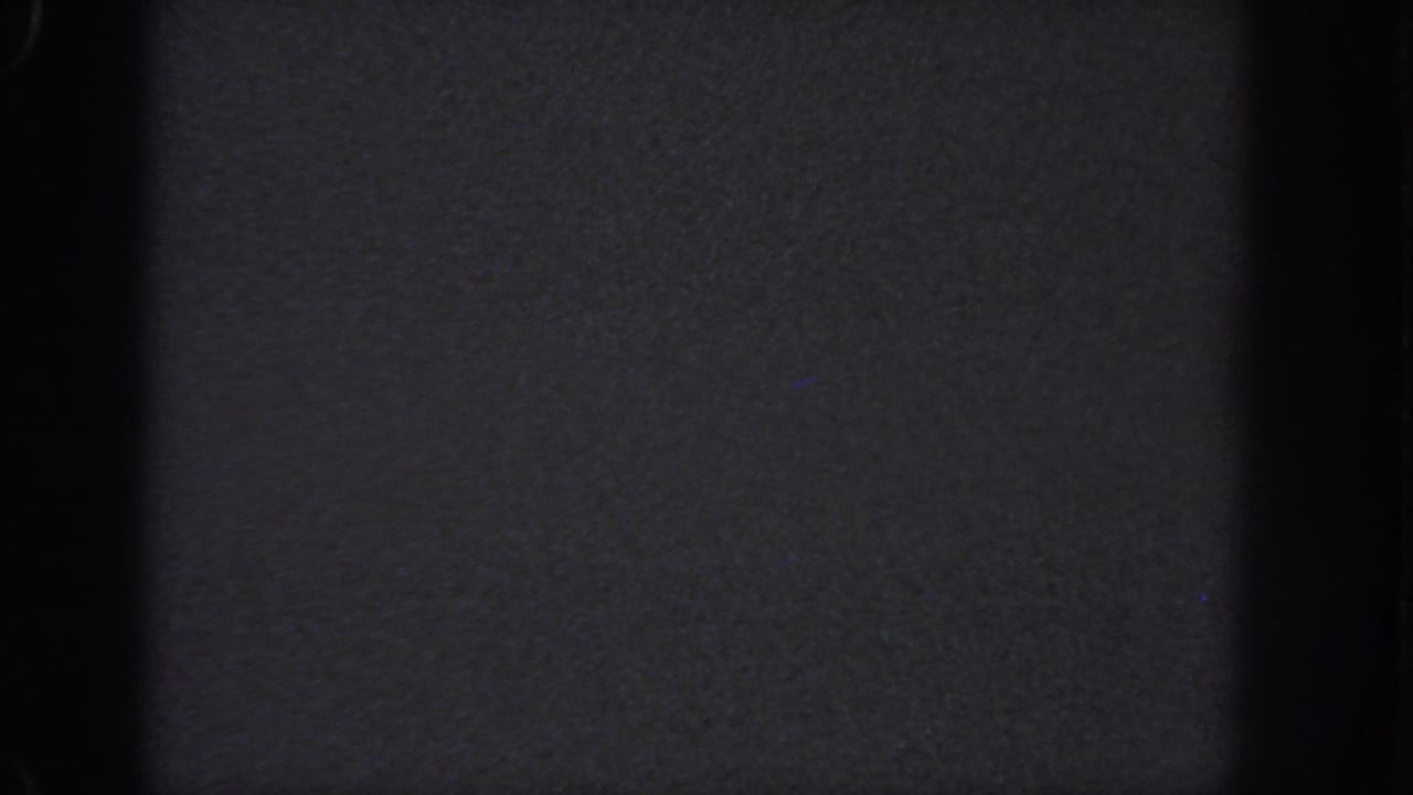 1951 Atlanta 8mm frame ending on a dark, low-exposure field with heavy grain, a black vertical band, and faint gray tonal texture.