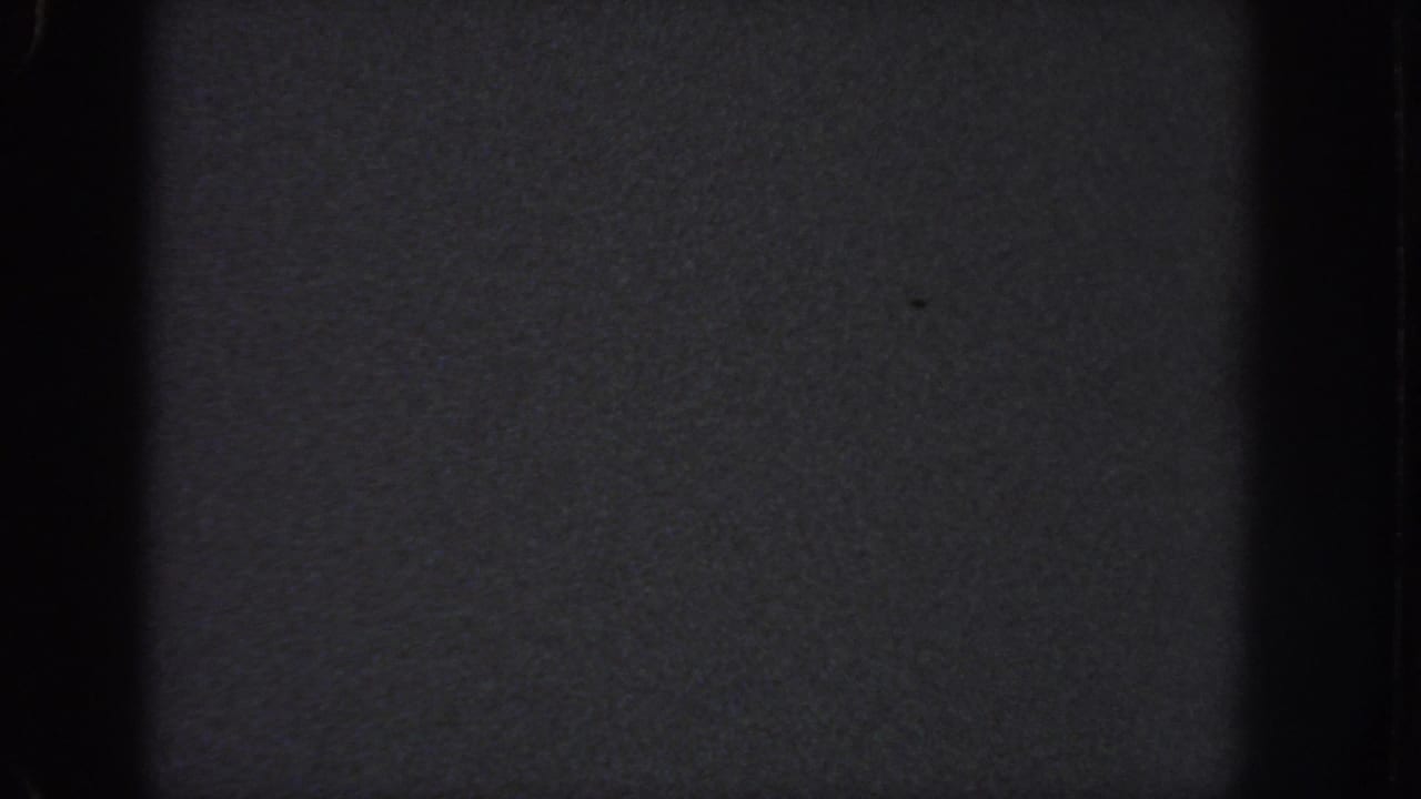 Dark blank 8mm frame from the 1951 Atlanta reel, showing grain, black gate edges, and faint surface specks.