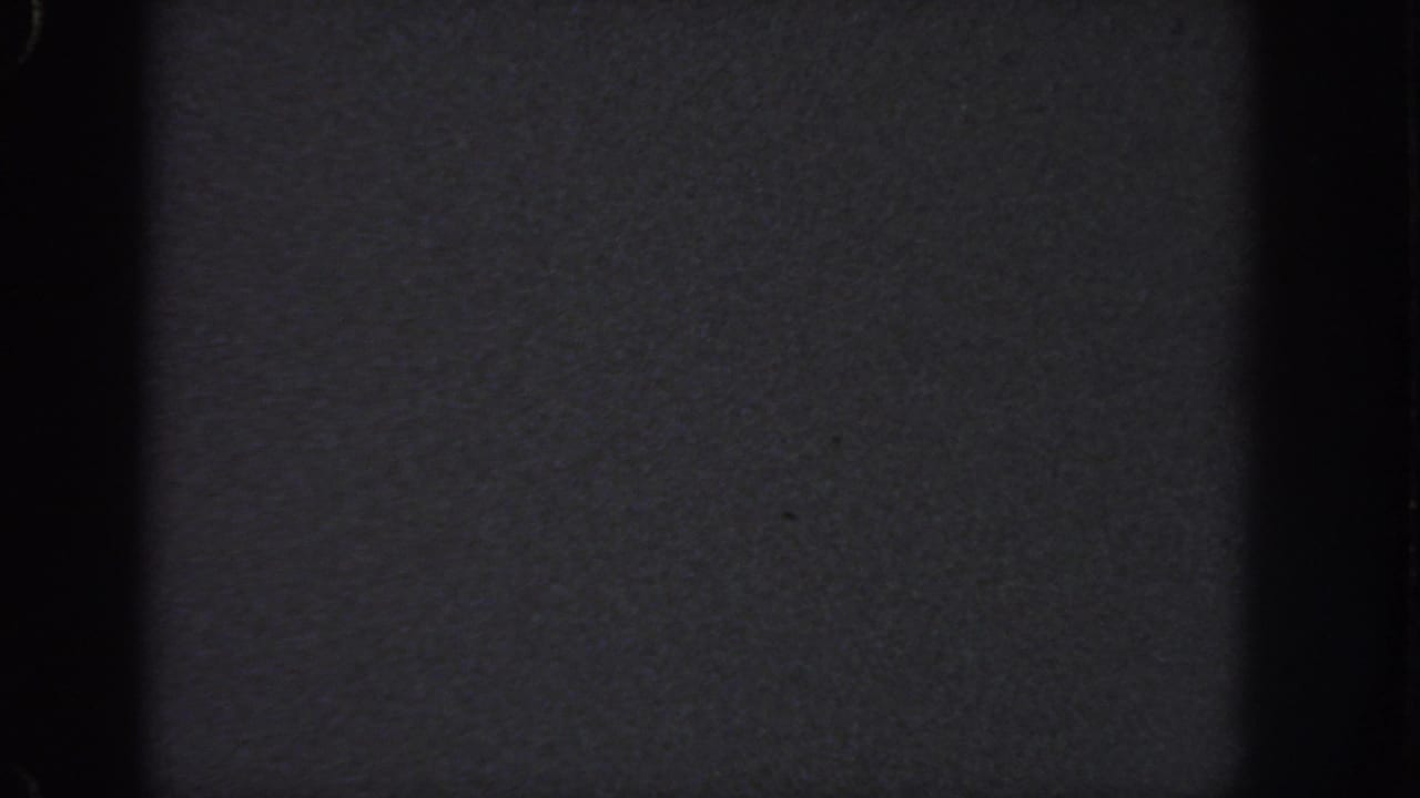 Near-black blank 8mm frame associated with the 1951 Atlanta reel, showing grain, specks, and strong vertical gate shadows.