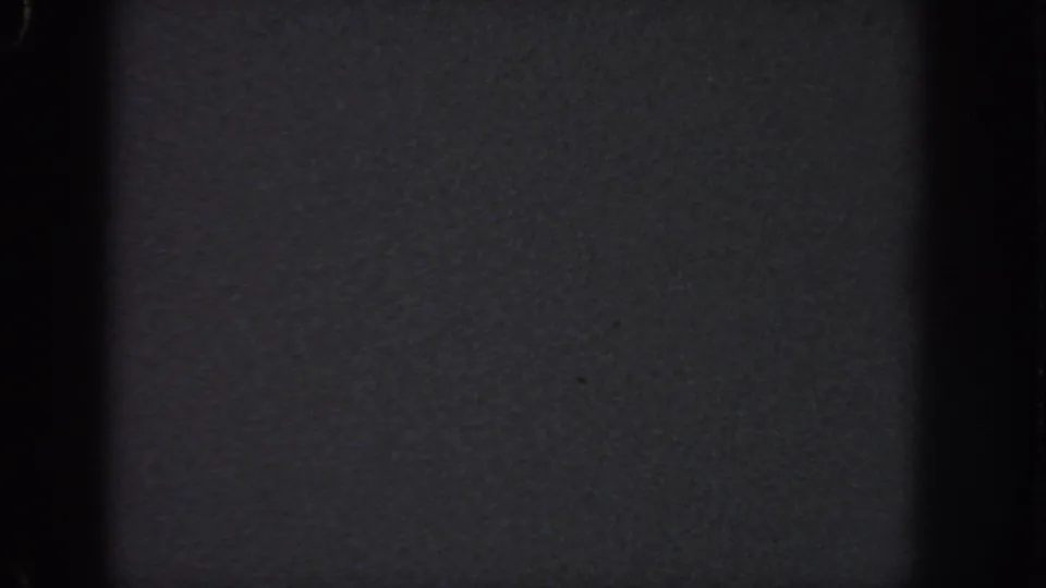 Near-black blank 8mm frame associated with the 1951 Atlanta reel, showing grain, specks, and strong vertical gate shadows.