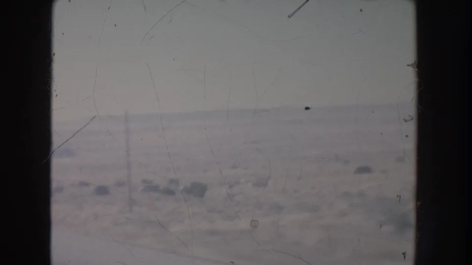 A framed 1951 New Mexico desert view shows low brush, flat ground, and a hazy horizon from a moving vehicle.