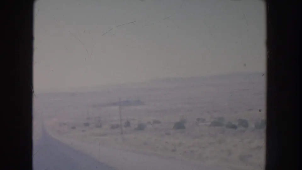 The 1951 New Mexico view shows a faint curving road or track crossing scrubby desert from a vehicle-window perspective.