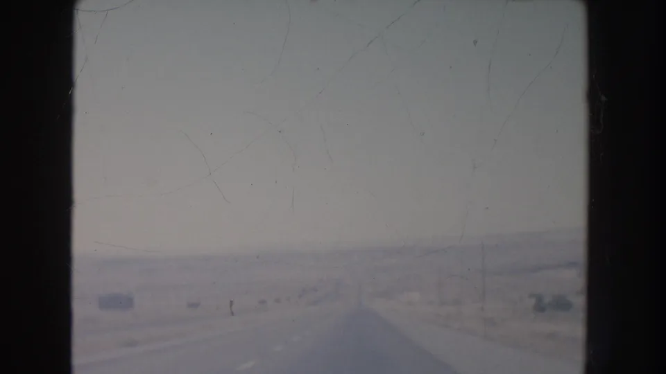 1951 New Mexico home-movie view from a moving car, looking down an empty highway through a washed-out desert setting.