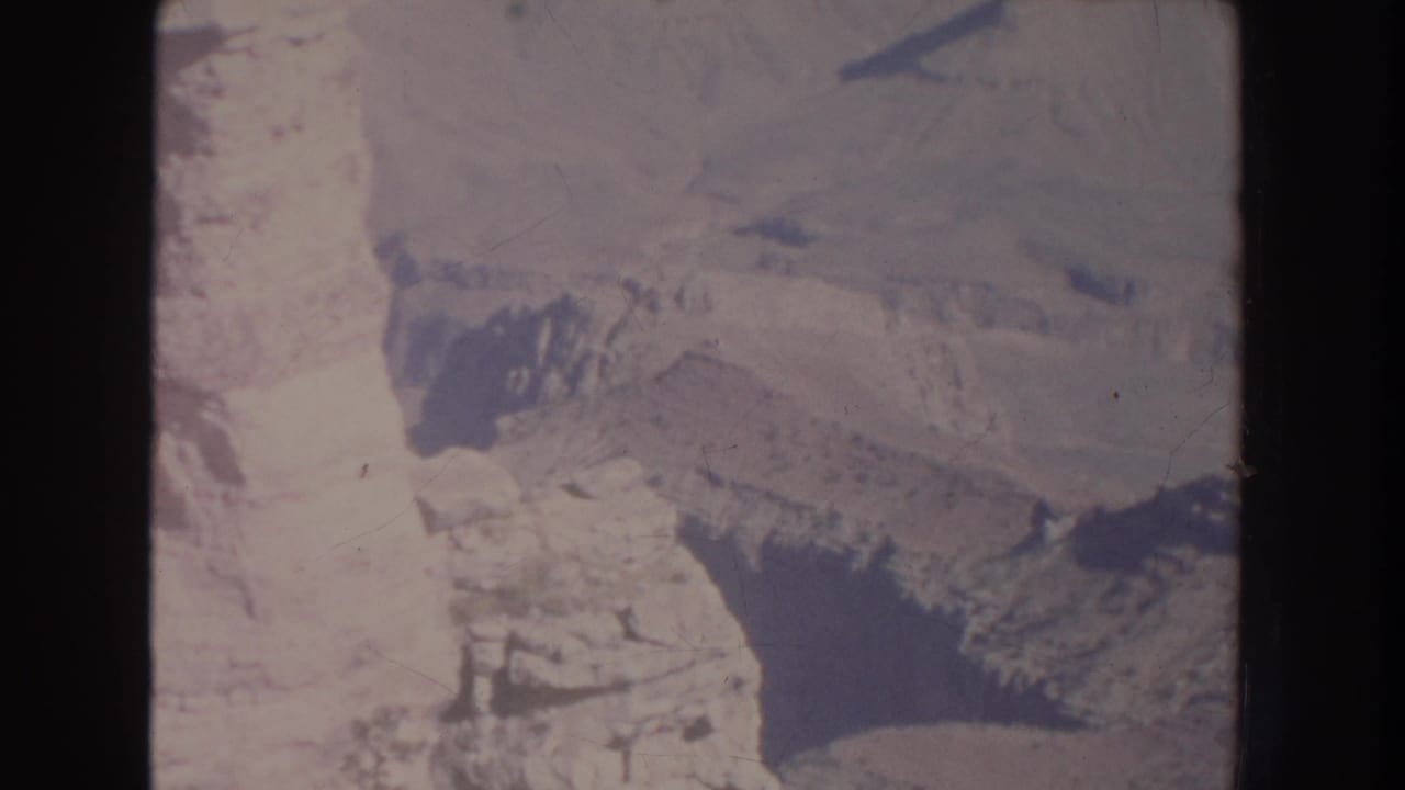 Aerial view of pale canyon walls and jagged rock ridges with dark shadowed cuts.