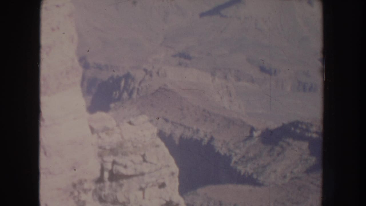 High aerial view across layered rocky terrain and shadowed canyon formations.
