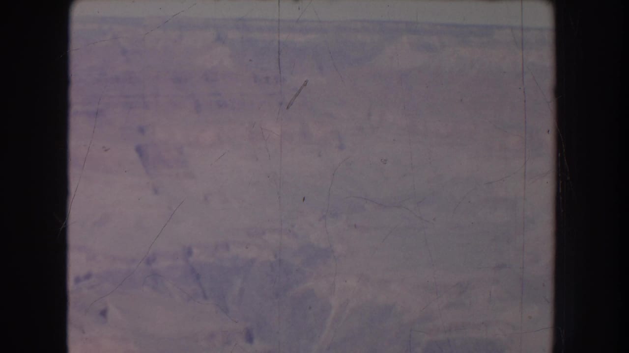 Faded canyon landscape seen through a film frame with no clear figures.