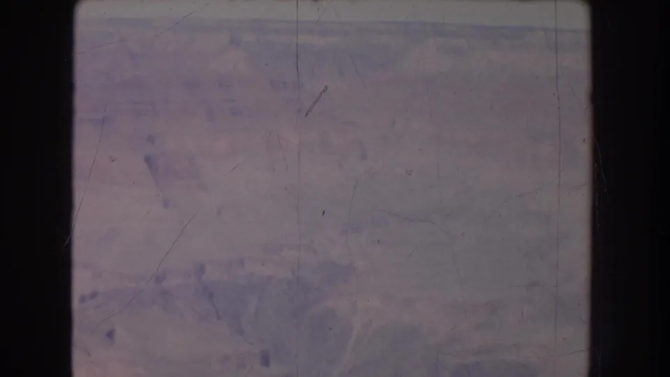 Faded 8mm view of a canyon landscape in New Mexico, with soft detail, scratches, and dark film borders.