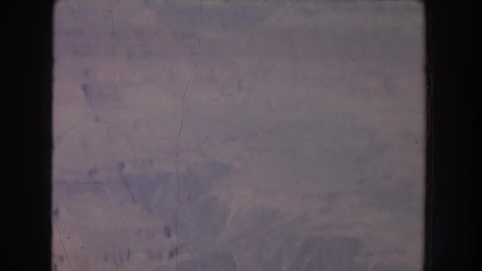Archival 8mm frame showing a muted canyon view, with soft exposure, visible grain, and no distinct people in this frame.