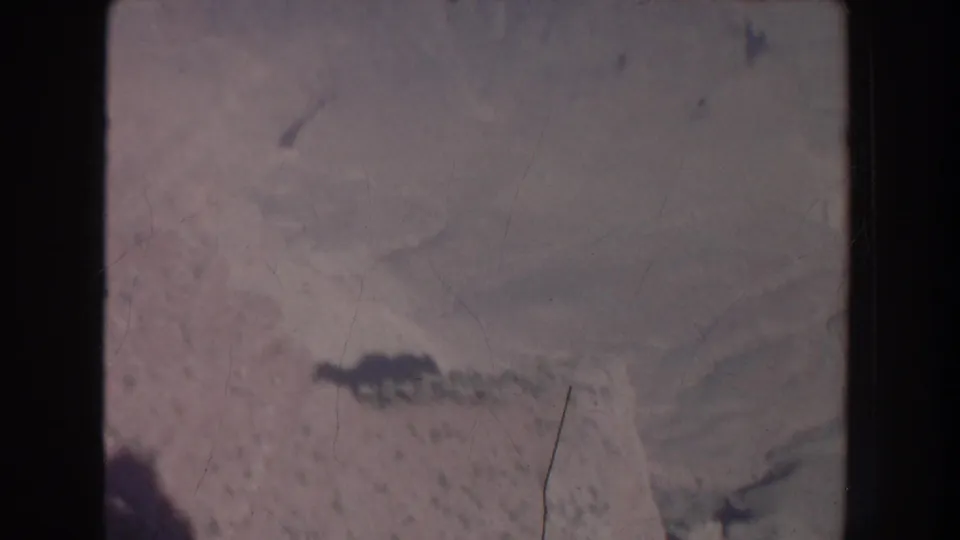 1951 New Mexico aerial home-movie frame with faint ridge lines, pale desert terrain, soft focus, and visible film wear.