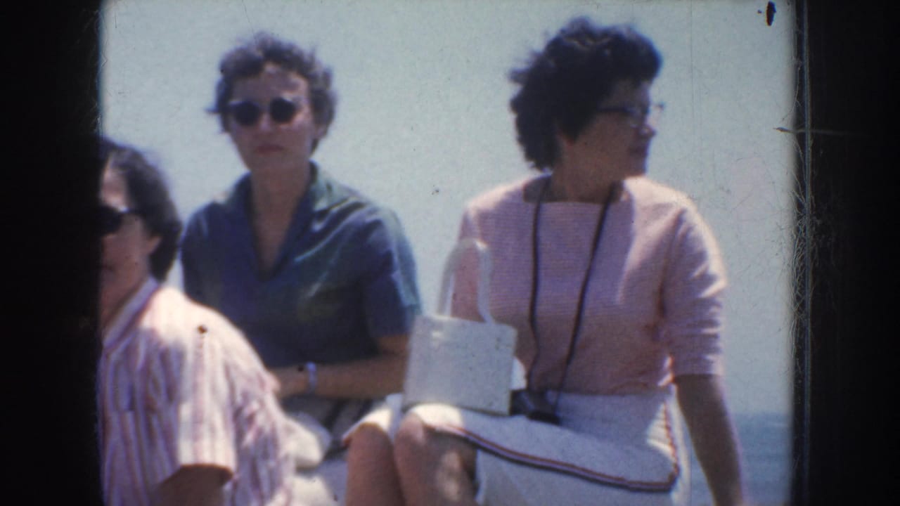 1952 California 8mm frame of adults seated outdoors, with women in sunglasses and skirts looking across a bright overlook.