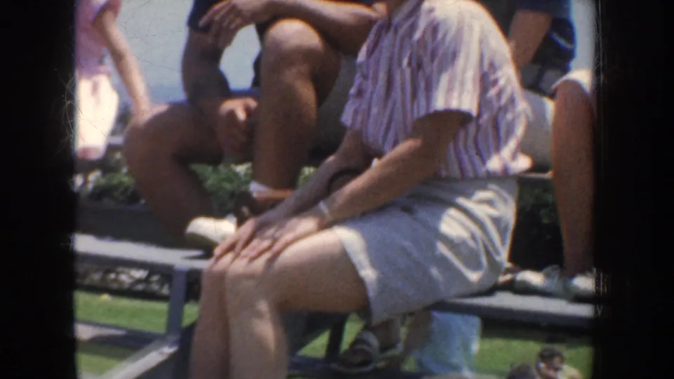 1952 California 8mm frame with a closer handheld view of adults seated on a bench in bright outdoor light.
