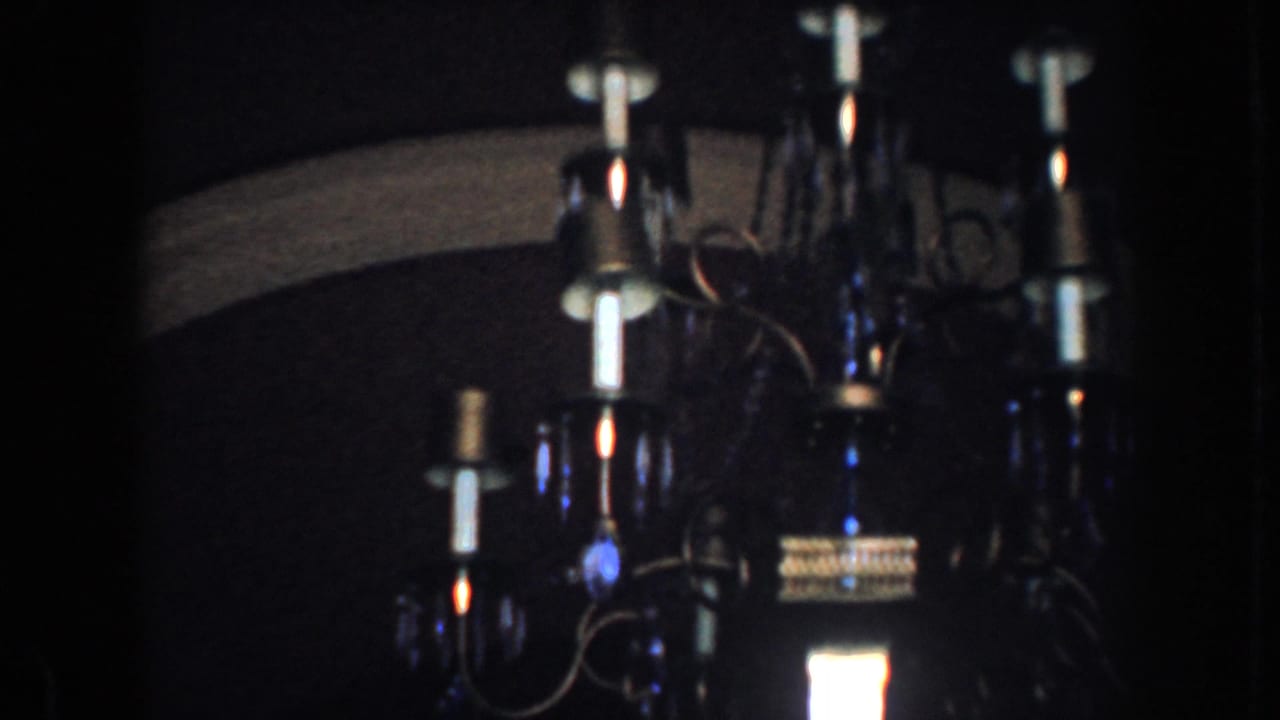 1952 California 8mm frame showing an ornate chandelier lit inside a dim private home interior.